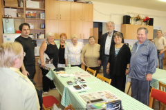 Közös kép az egyesület tagjai és a Labrador KFT munkatársaival, körül állják az asztalt.